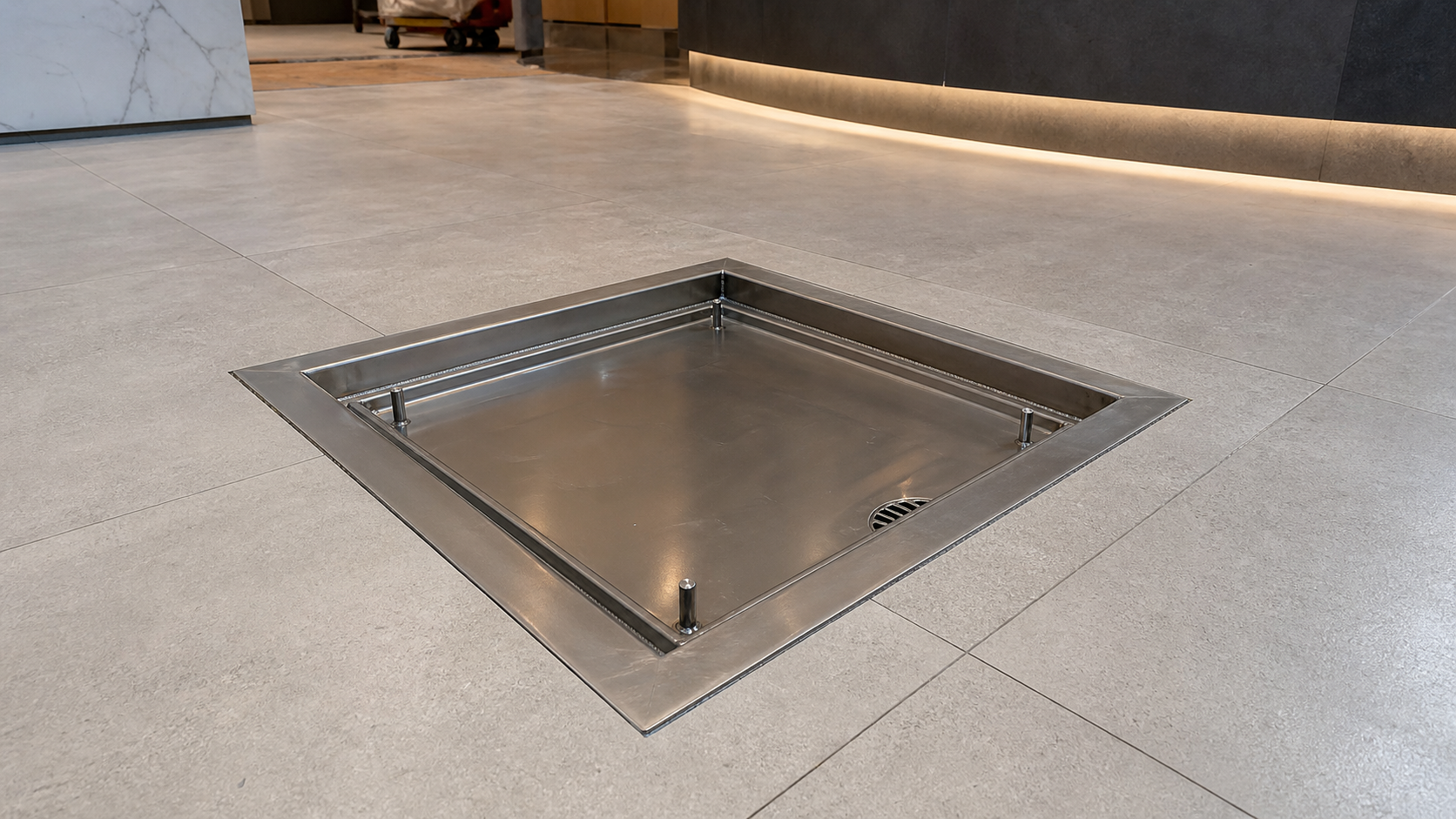 Recessed stainless steel manhole cover installed flush with a commercial tile floor