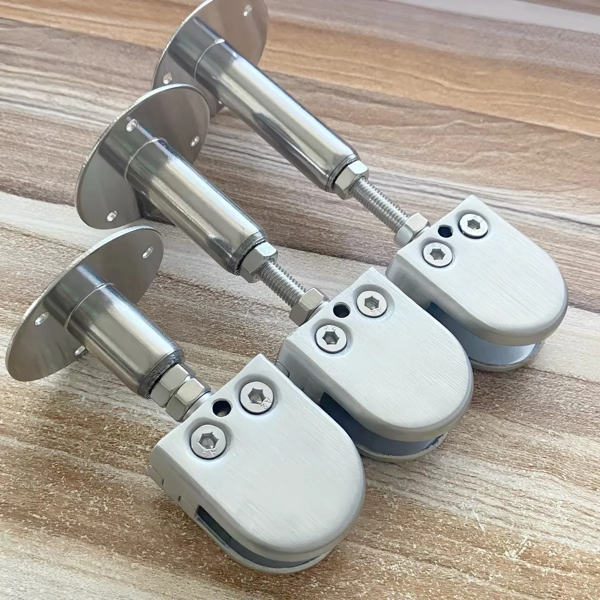 Three adjustable stainless steel wall-mounted glass support brackets