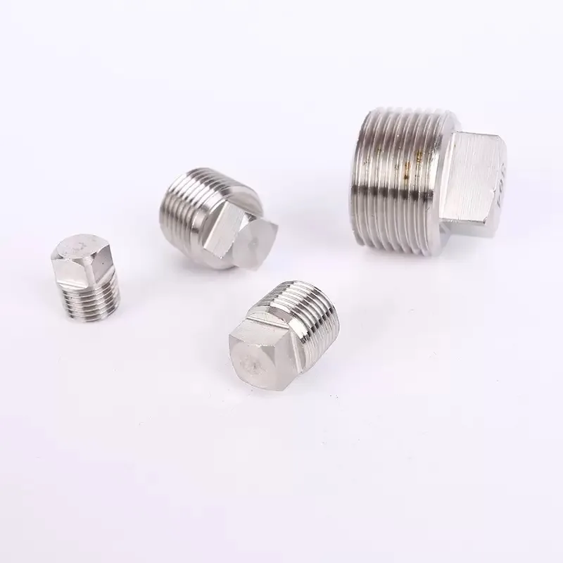 Close-up of square drive heads and male threads on stainless steel pipe plugs