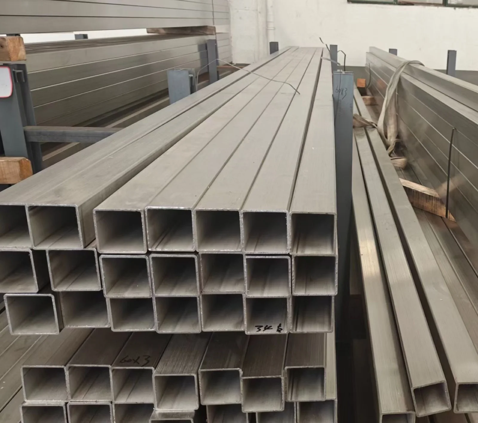 Stainless steel welded square tubes stacked with cut ends visible