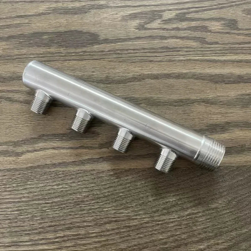 Four-outlet stainless steel water distribution manifold showing branch spacing